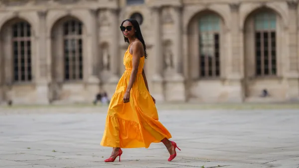 Emilie Joseph @in_fashionwetrust wears a yellow asymmetric cut-out midi dress from Mango, red mesh toe-cap strappy pumps heels shoes from Bottega Veneta, a gold ring, on June 05, 2021 in Paris, France.