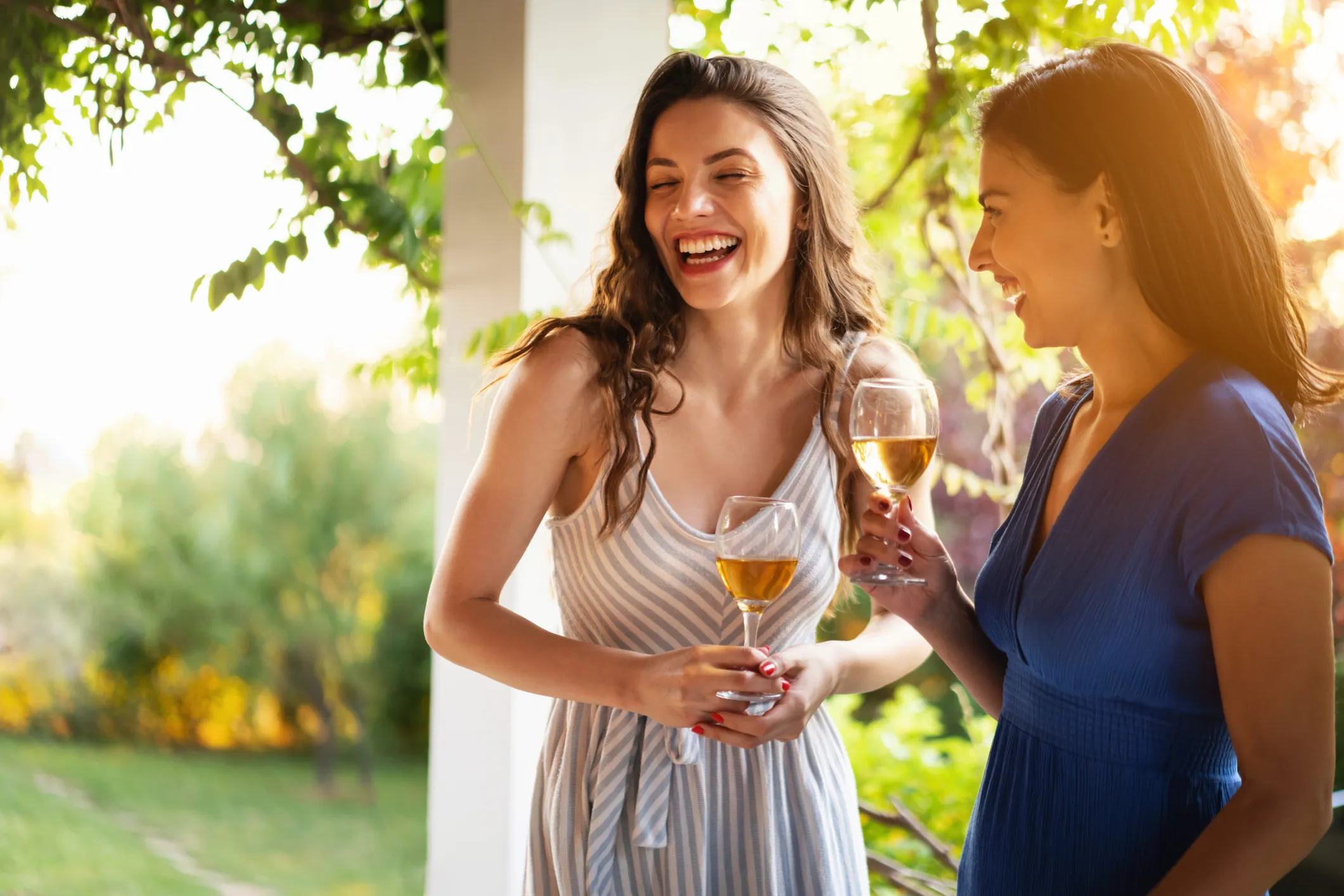 Serene female Caucasian friends, drinking wine while having a casual conversation during summer garden party