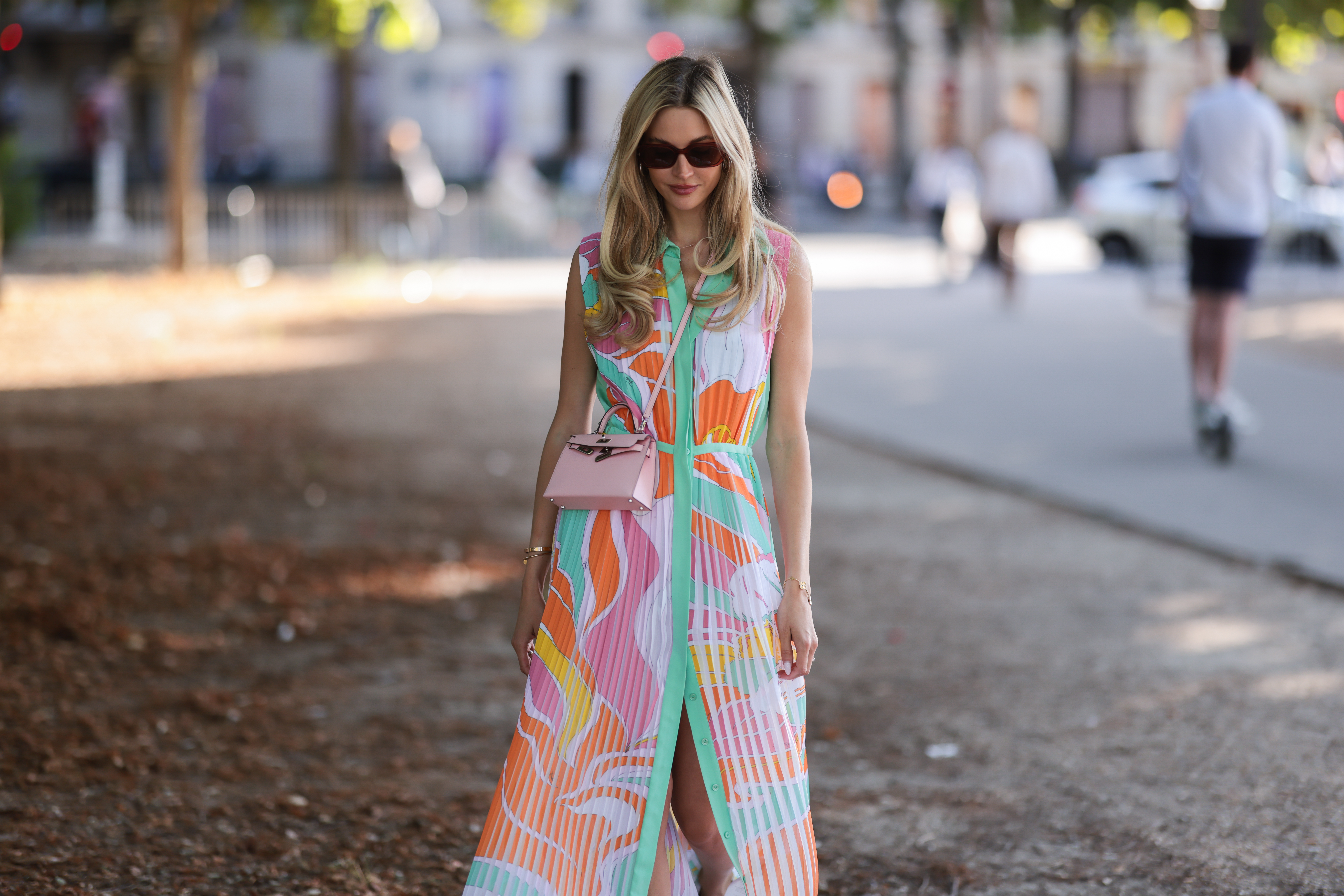 Mandy Bork seen wearing brown sunglasses from Tom Ford, silver earrings, a colorful buttoned / pleated / sleeveless long dress from Emilio Pucci, a pale pink leather Hermes Kelly mini bag, a gold diamond Cartier Love bracelet, a gold Cartier Juste Un Clou bracelet and white creme sandals from Chanel, during Paris Fashion Week - Haute Couture Fall Winter 2022 2023, on July 06, 2022 in Paris, France.