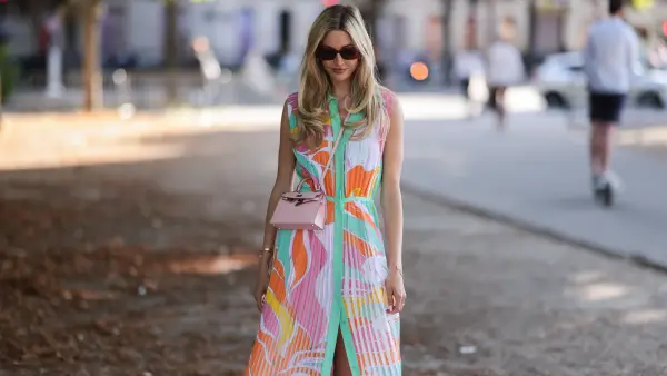 Mandy Bork seen wearing brown sunglasses from Tom Ford, silver earrings, a colorful buttoned / pleated / sleeveless long dress from Emilio Pucci, a pale pink leather Hermes Kelly mini bag, a gold diamond Cartier Love bracelet, a gold Cartier Juste Un Clou bracelet and white creme sandals from Chanel, during Paris Fashion Week - Haute Couture Fall Winter 2022 2023, on July 06, 2022 in Paris, France.