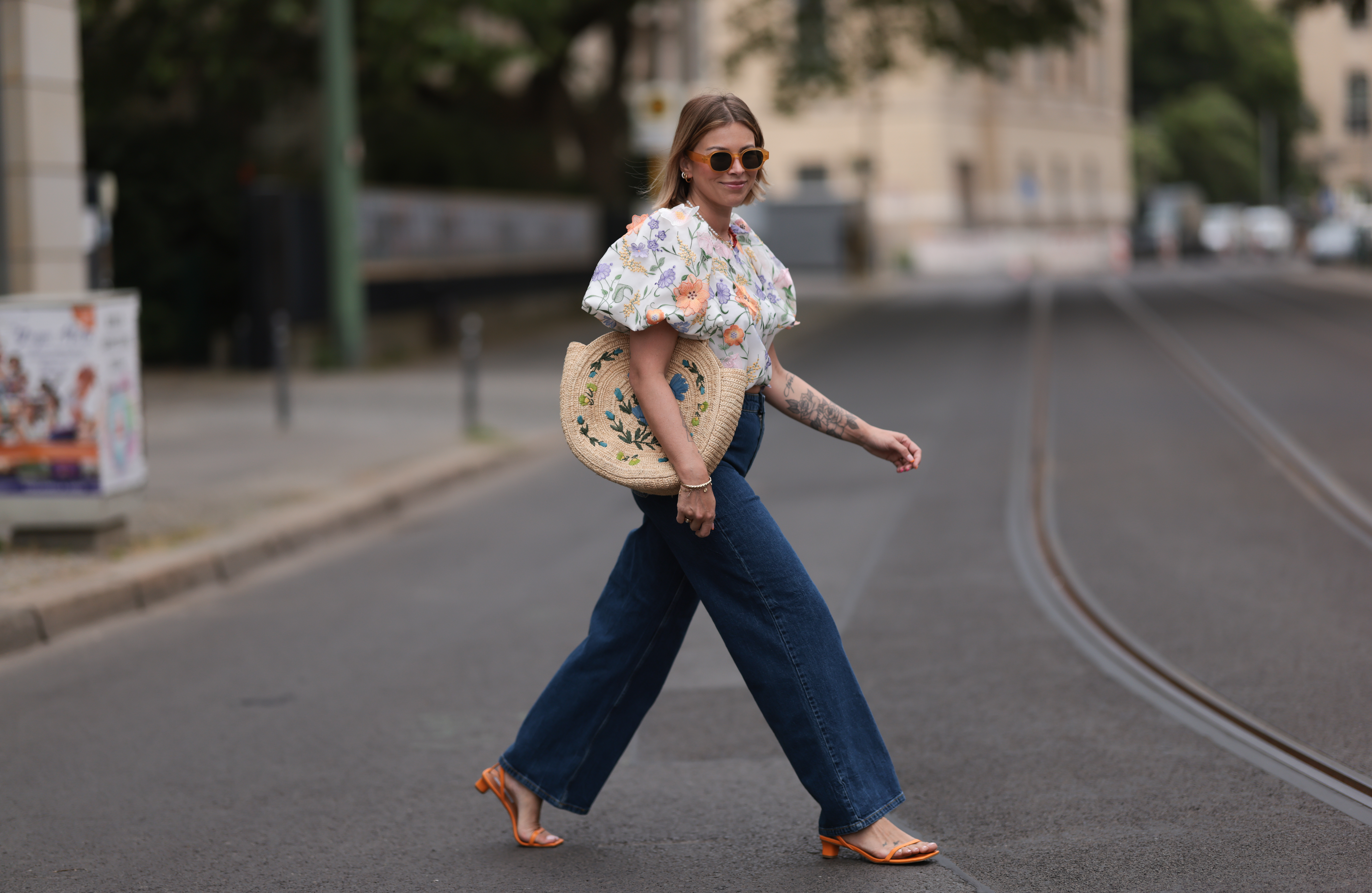 Aline Kaplan wearing Baum & Pferdgarten wide leg blue denim pants, & other stories white flower pattern cropped blouse and orange summer heels and Mango orange black shades on June 06, 2023 in Berlin, Germany.