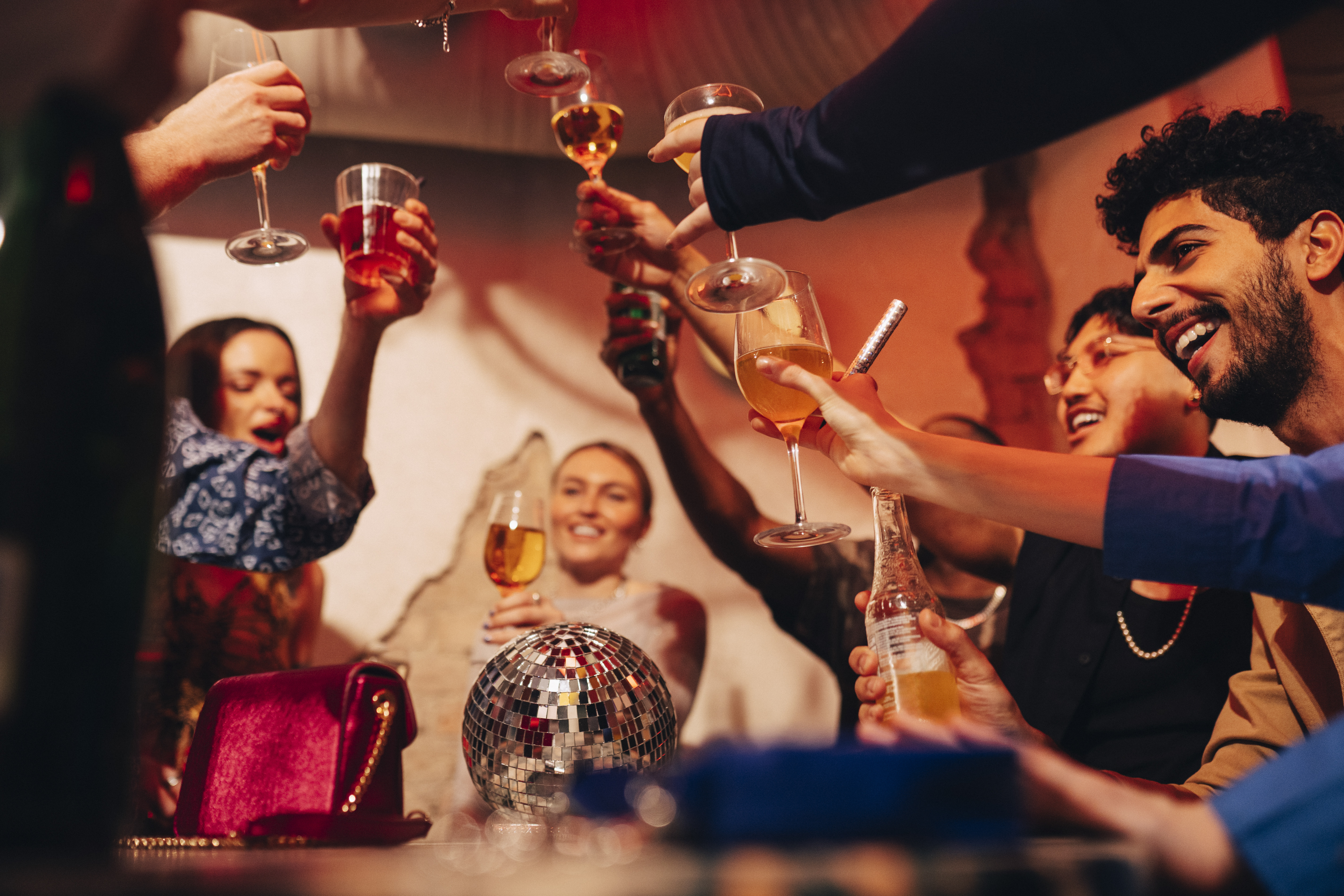 Cheerful male and female friends toasting drinks while celebrating at bar