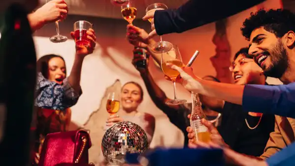 Cheerful male and female friends toasting drinks while celebrating at bar