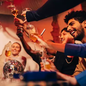 Cheerful male and female friends toasting drinks while celebrating at bar