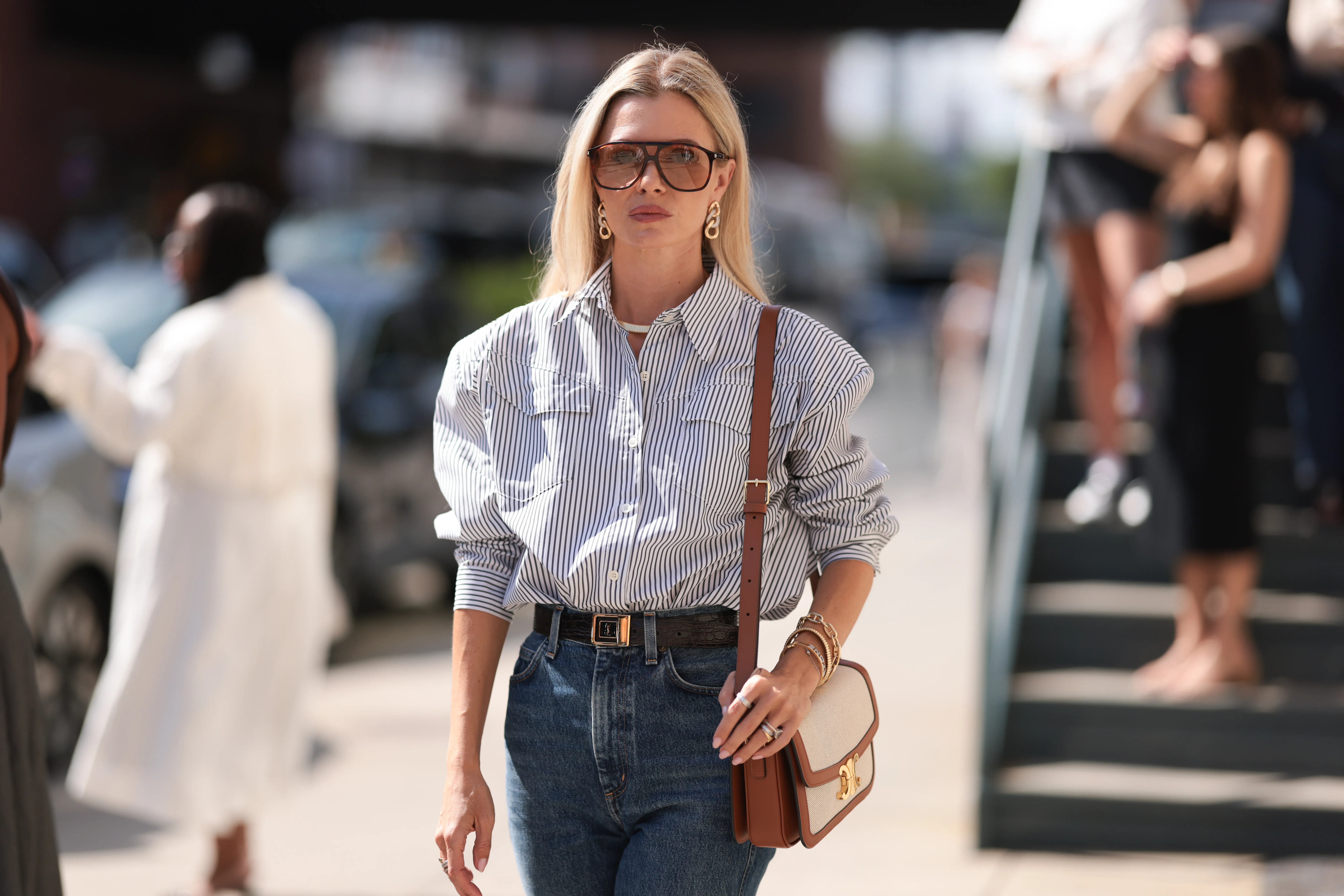 Fashion Week Guest seen wearing a white and darkblue blouse, denim blue jeans, black heels, white and brown Celine handbag, sunglasses and a black YSL belt outside Brandon Maxwell show during New York Fashion Week on September 06, 2024 in New York City.