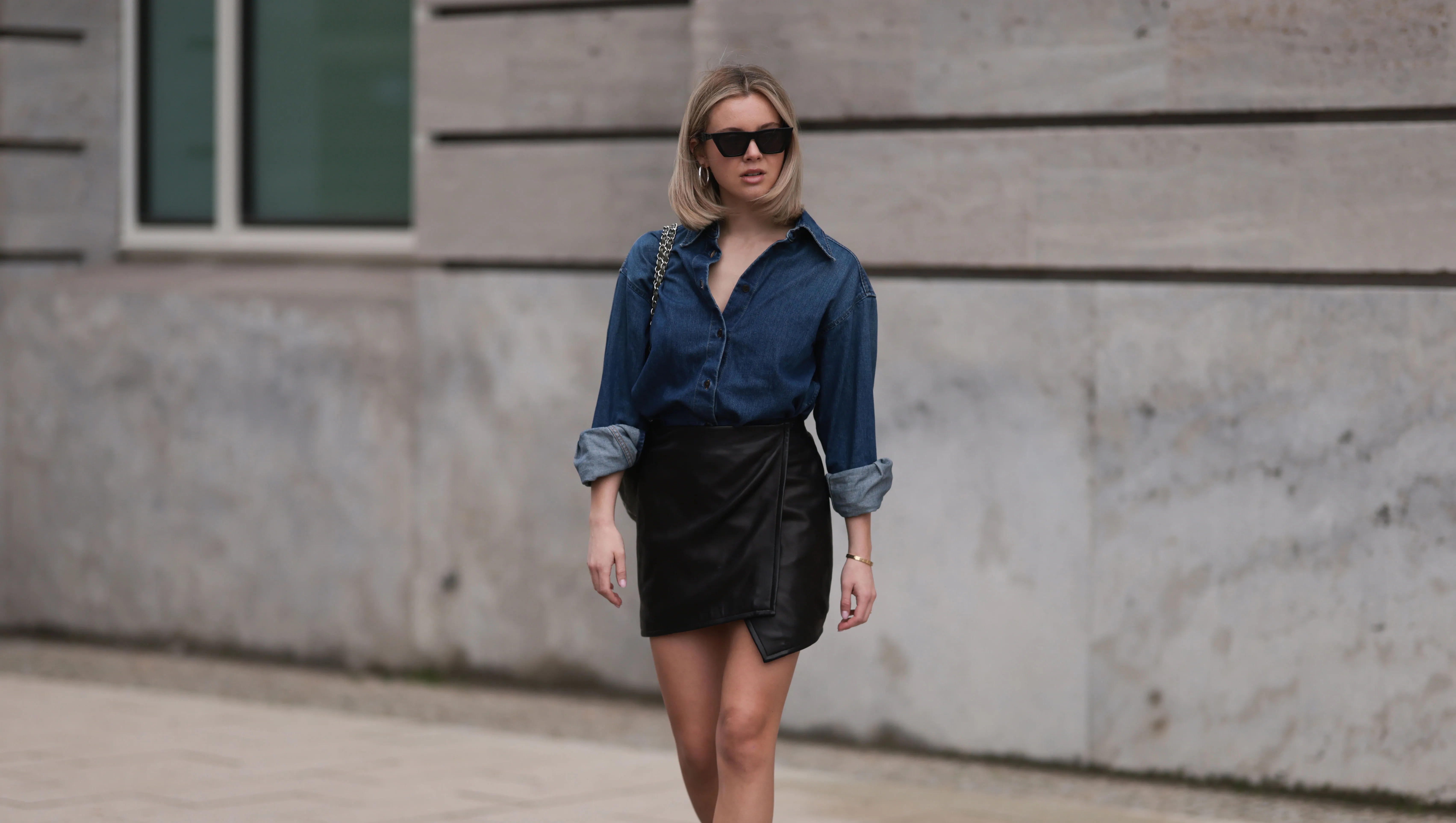 HAMBURG, GERMANY - APRIL 05: Isabelle Hartmann seen wearing Celine black sunglasses, Closed dark blue denim buttoned shirt, By Aylin König black leather short skirt, Chanel dark green shiny leather handbag, white cotton socks and Chanel black leather logo loafers on April 05, 2024 in Hamburg, Germany. (Photo by Jeremy Moeller/Getty Images)