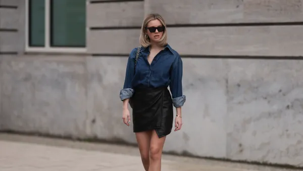 HAMBURG, GERMANY - APRIL 05: Isabelle Hartmann seen wearing Celine black sunglasses, Closed dark blue denim buttoned shirt, By Aylin König black leather short skirt, Chanel dark green shiny leather handbag, white cotton socks and Chanel black leather logo loafers on April 05, 2024 in Hamburg, Germany. (Photo by Jeremy Moeller/Getty Images)