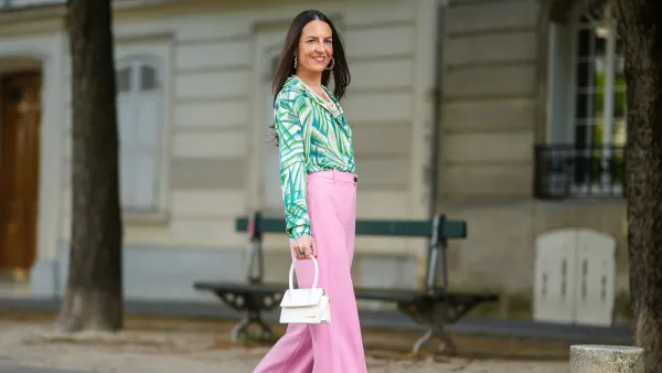 PARIS, FRANCE - MAY 23: Alba Garavito Torre wears gold and pearls earrings, a white pearls necklace, a white with green tree leaf pattern shirt, pale pink flared suit pants, gold rings, a green ring, a pink ring, a gold Love Cartier bracelet, gold bracelets, a white matter leather Chiquito Medium Jacquemus handbag, dark green satin Manolo Blahnik pumps shoes, on May 23, 2021 in Paris, France. (Photo by Edward Berthelot/Getty Images)