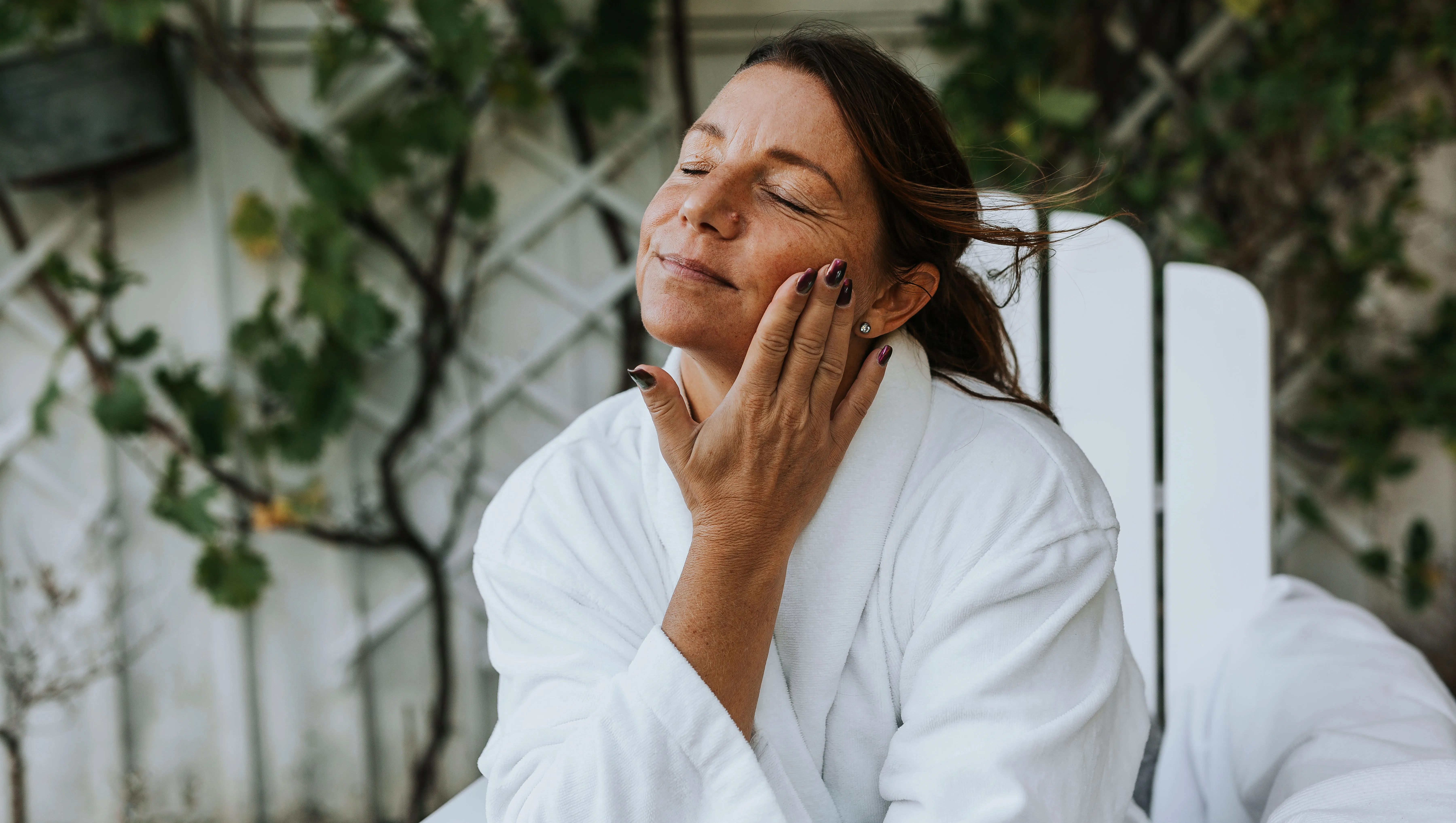Smiling woman applying face cream - stock photo