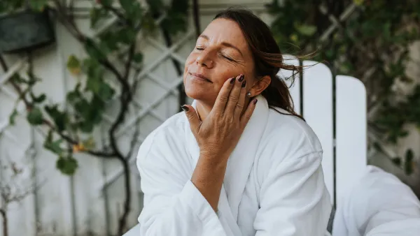 Smiling woman applying face cream - stock photo