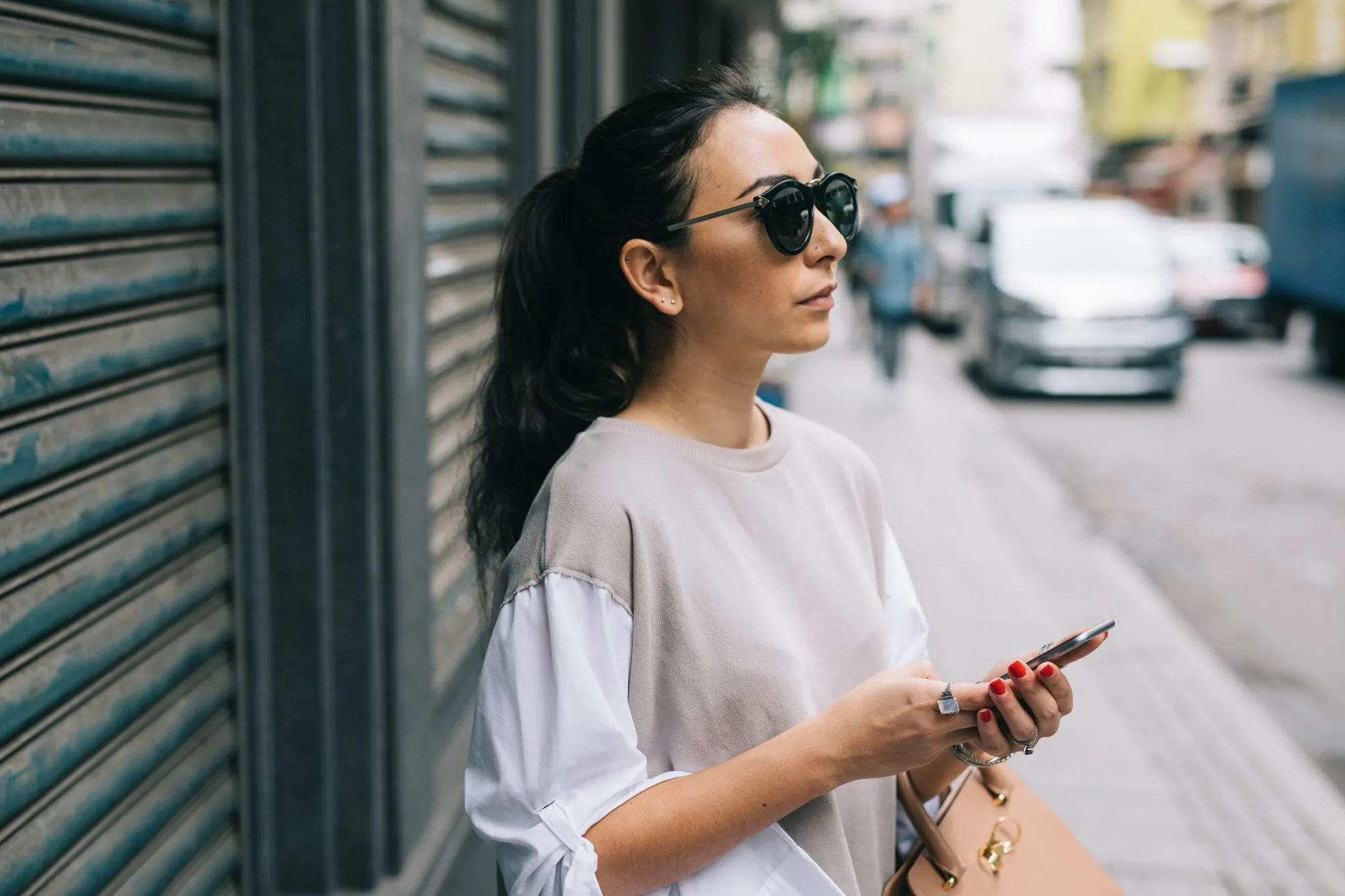 Young woman waiting for taxi in Hong Kong, using smartphone