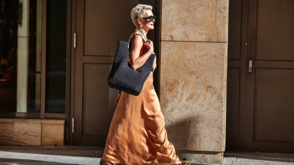 Stylish Mature Woman with Short Hairstyle Walks, Wearing Summer Beige maxi Dress and Large Handbag. Fashion Mode in City.
