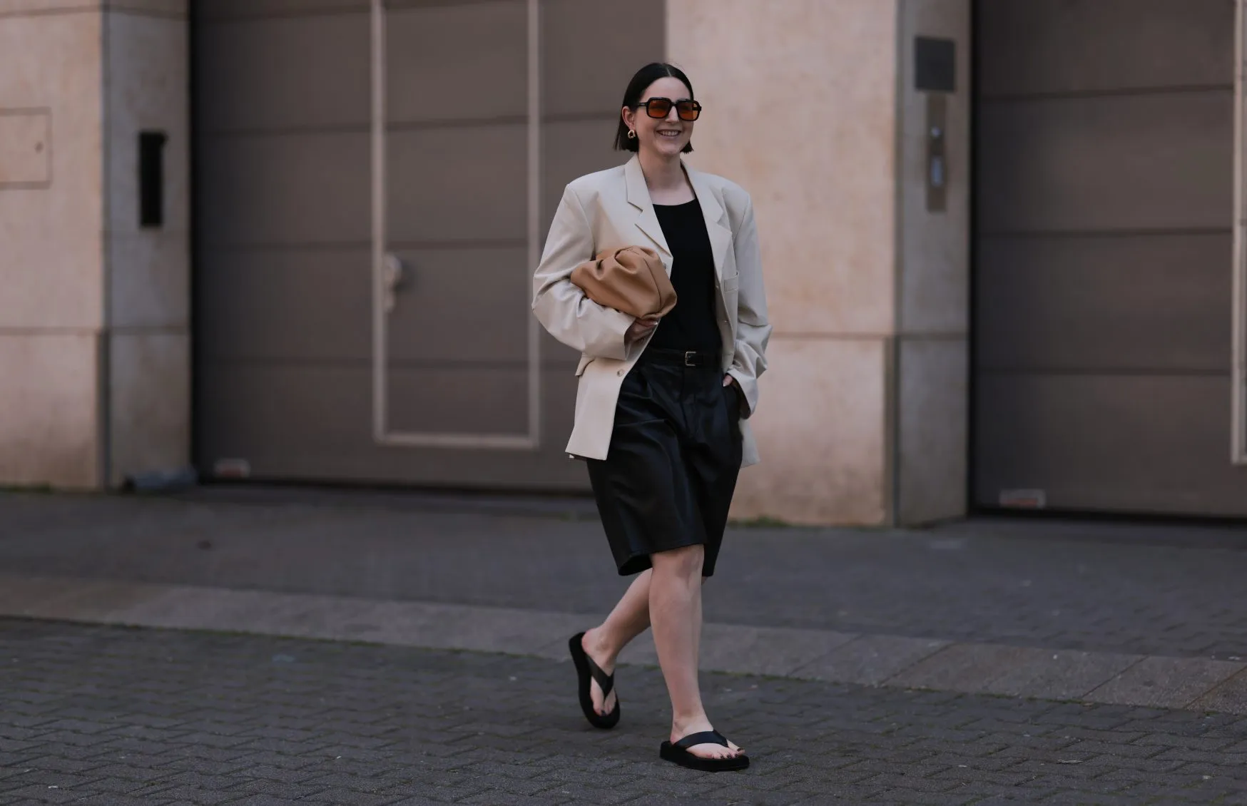 DUSSELDORF, GERMANY - MAY 28: Maria Barteczko wearing Oversized Studio light beige cut out blazer, ARKET black top, Zara black belted leather culottes trousers, Mango beige leather pouch, The Row black plateau flip flops, Celine gold earrings and Spitfire orange black framed sunglasses on May 28, 2023 in Dusseldorf, Germany. (Photo by Jeremy Moeller/Getty Images)