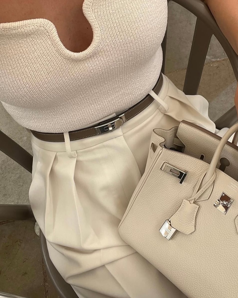 hermes etoupe kelly belt with a craie brikin 25 on woman with a cream colored outfit