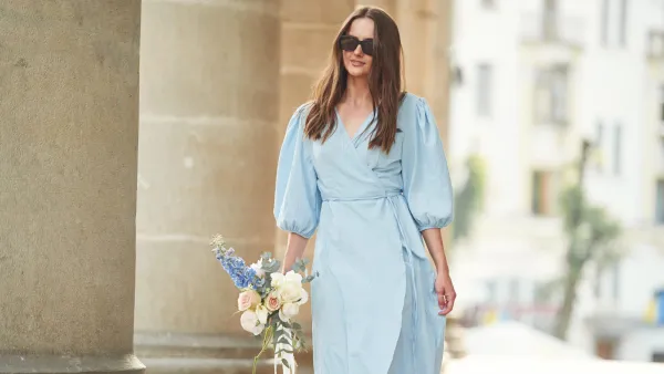 In dress. Beautiful woman is with flowers in hands outdoors.