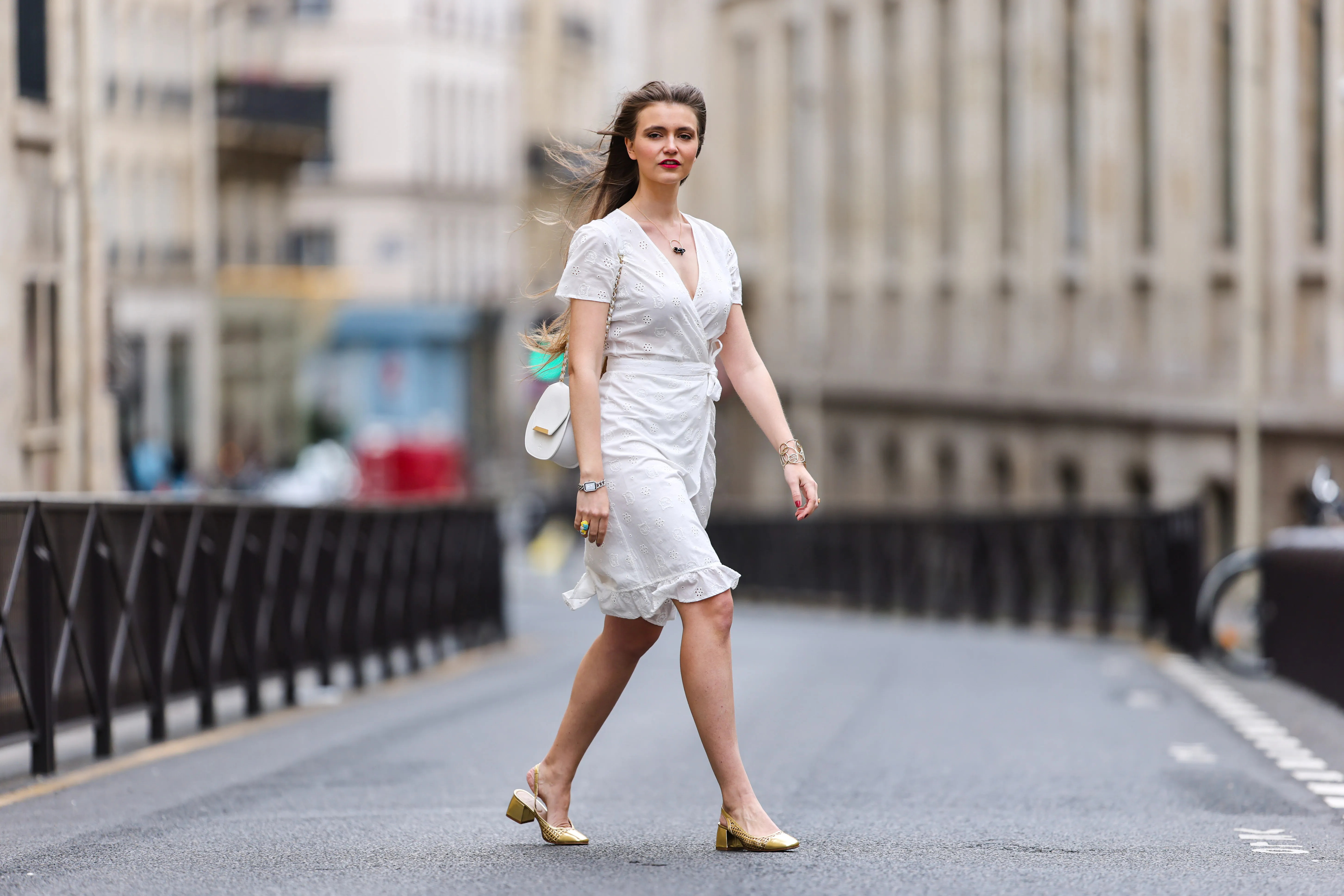 Fashion blogger @hippolyt.e wears a white lace with belted short ruffled dress from Nach Bijoux, rings and necklace from Nach Bijoux, a gold Chanel bracelet, a white matter leather shoulder bag from Charlie Paris, a silver and black Chanel watch, golden shoes, on May 20, 2021 in Paris, France.