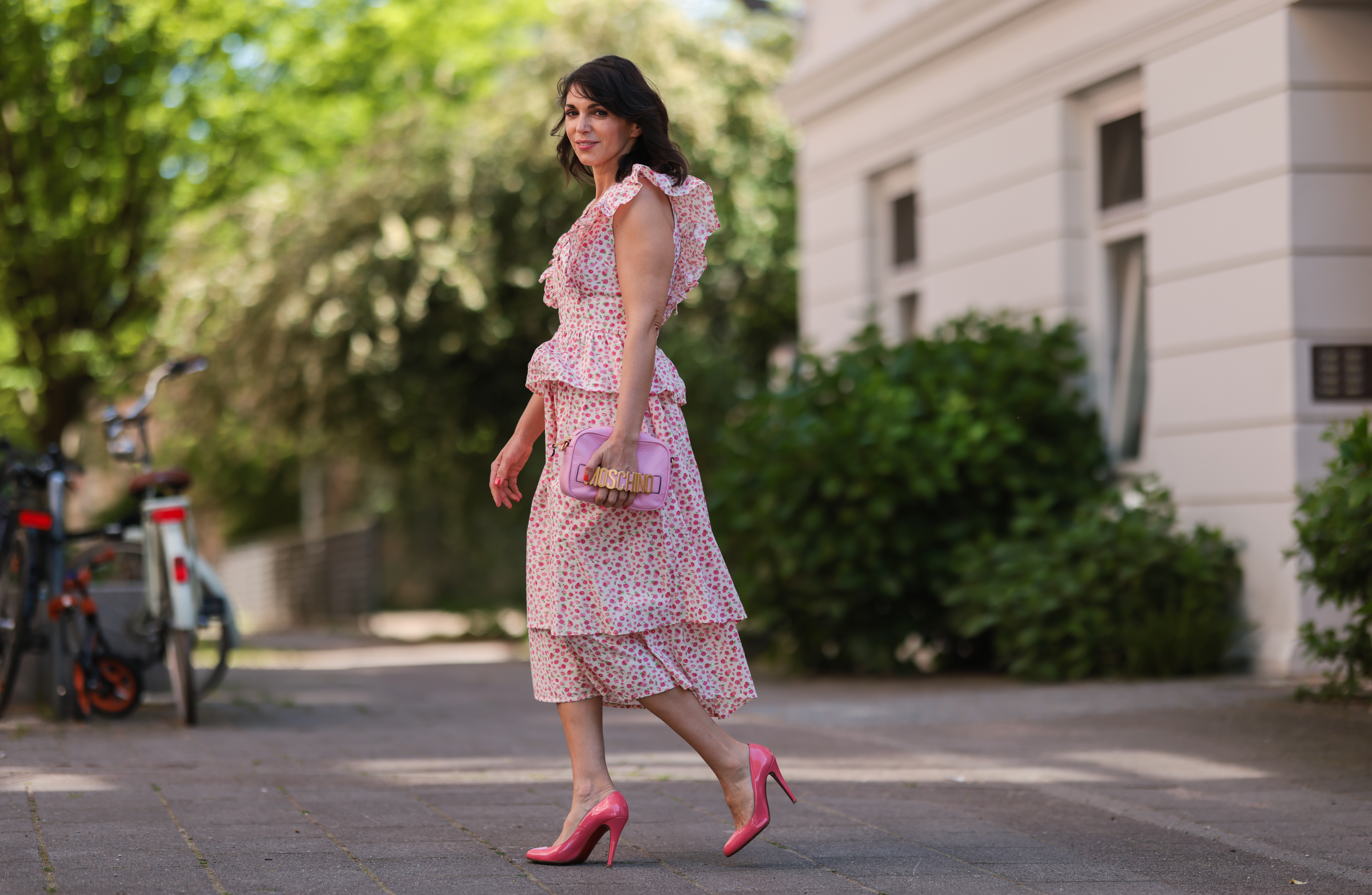 Anna Wolfers wearing white and pink ruffle dress via Goldig Shop, pink Moschino clutch and pink heels on May 31, 2021 in Hamburg, Germany.