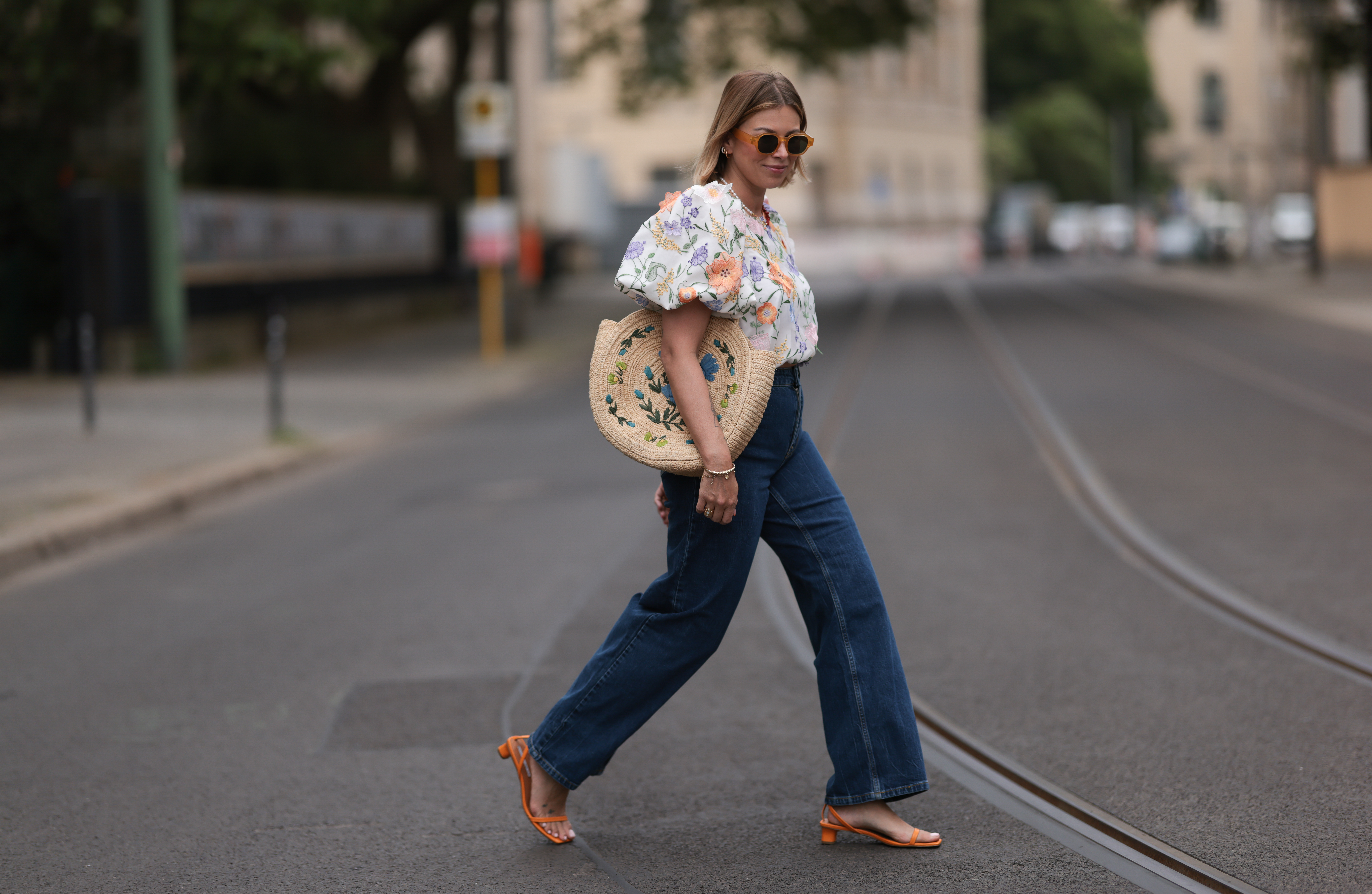 Aline Kaplan wearing Baum & Pferdgarten wide leg blue denim pants, & other stories white flower pattern cropped blouse and orange summer heels and Mango orange black shades on June 06, 2023 in Berlin, Germany.