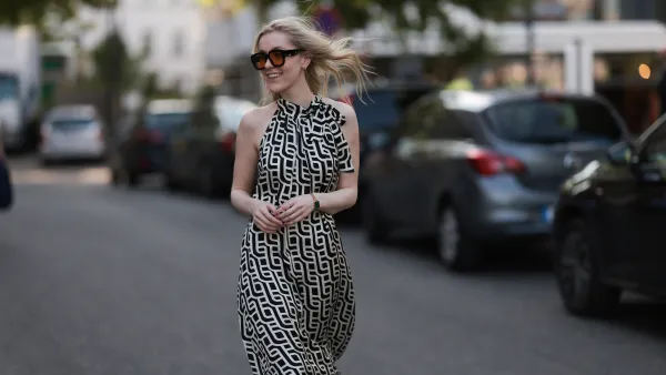 BERLIN, GERMANY - JUNE 19: Lil Paulin is seen wearing oversized black square-framed sunglasses with orange lenses and wide temples, gold hoop earrings, a flowy sleeveless maxi dress with a halter neck and a geometric black and white pattern, a gold rectangular watch from Daniel Wellington, and several filigree silver rings on June 19, 2025 in Berlin, Germany. (Photo by Jeremy Moeller/Getty Images)