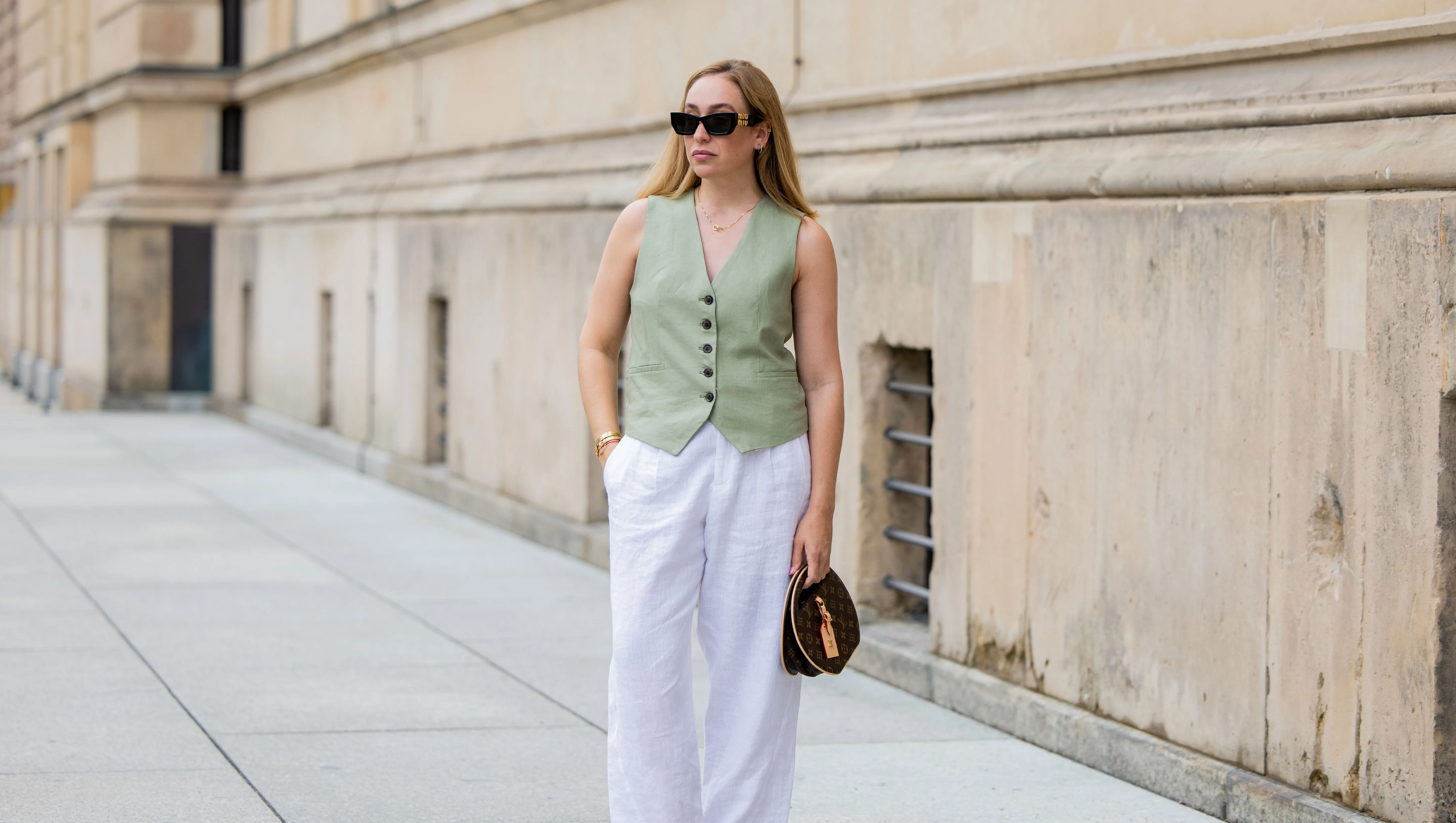 BERLIN, GERMANY - JULY 01: Sonia Lyson wears pink black Chanel ballerinas, white linen pants & green vest Zara, Louis Vuitton bag, sunglasses Miu Miu during the Berlin Fashion Week SS25 on July 01, 2024 in Berlin, Germany. (Photo by Christian Vierig/Getty Images)