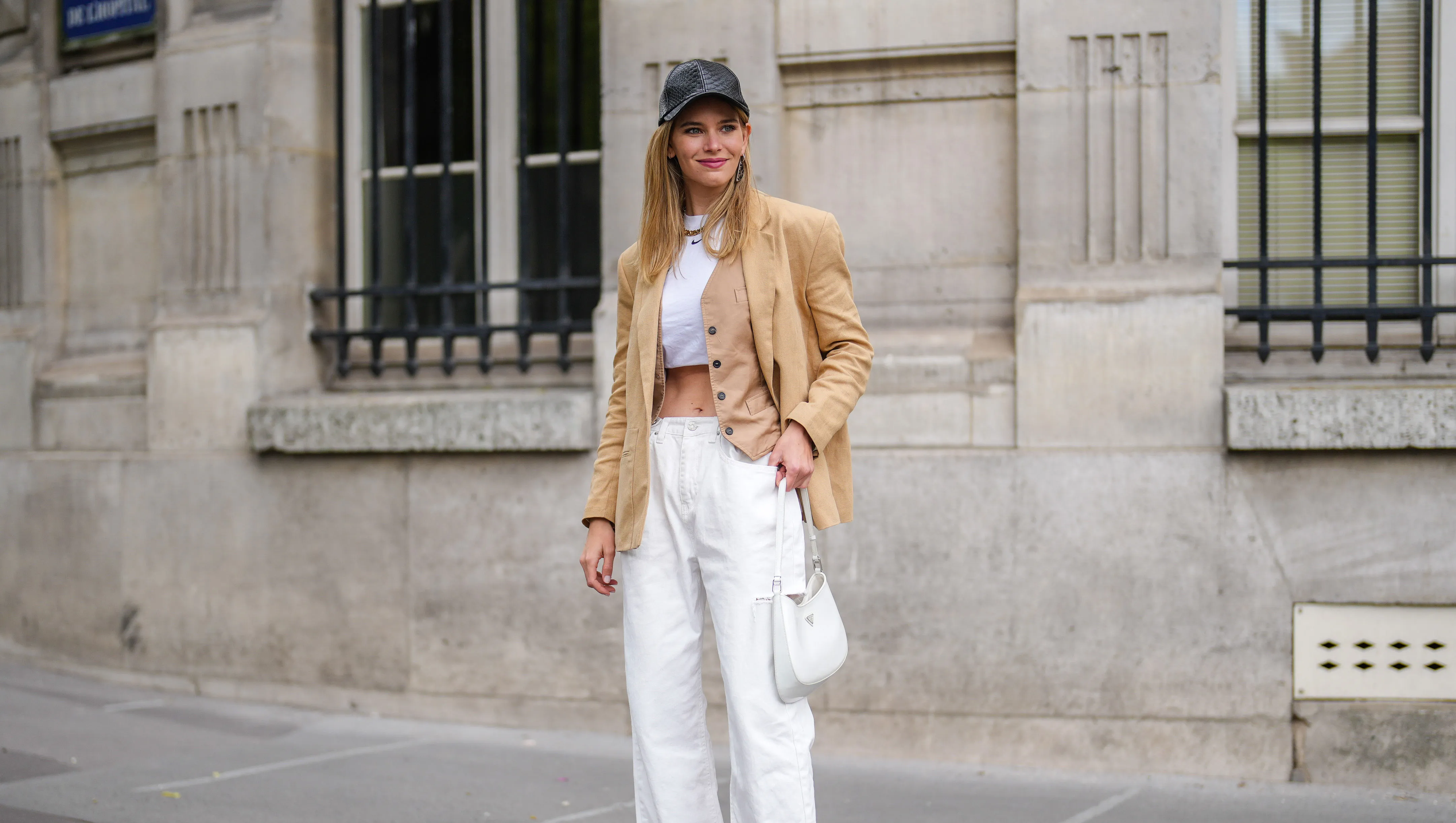 PARIS, FRANCE - MAY 16: Natalia Verza @mascarada.paris wears, a black leather cap, a beige linen oversized blazer jacket from Aeron, a white cropped t-shirt, white ripped denim jeans pants, a white Prada Cleo bag, high heels pointed pumps shoes from Louboutin, on May 16, 2021 in Paris, France. (Photo by Edward Berthelot/Getty Images)