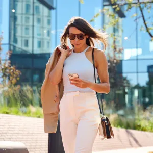 Stylish woman using phone while walking in the city - stock photo