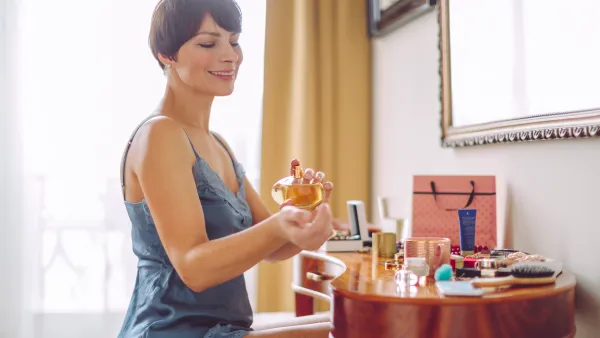 Woman at makeup table at home applying perfume