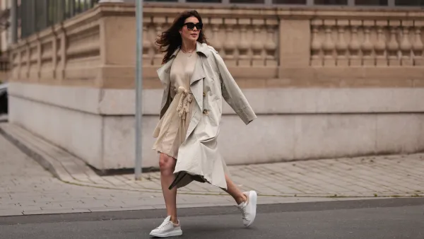 DUSSELDORF, GERMANY - AUGUST 07: Ira Meindl wearing Mango beige trenchcoat, Hermes grey leather bag, Alexander McQueen white sneaker, beige dress and Celine shades on August 07, 2021 in Dusseldorf, Germany. (Photo by Jeremy Moeller/Getty Images)