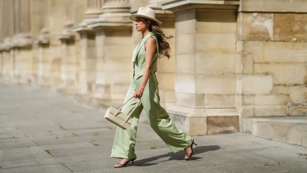 PARIS, FRANCE - MAY 29: Angela Gonzalez wears a beige suede Lack Of Color hat, earrings, a black off shoulder top, a pale green buttoned blazer jacket sleeveless from Nasty Gal, pale green matching Nasty Gal flared pants, a gold chain bracelet, a beige shiny leather Mango handbag, brown shiny leather strappy hells Na-Kd sandals, on May 29, 2021 in Paris, France. (Photo by Edward Berthelot/Getty Images)