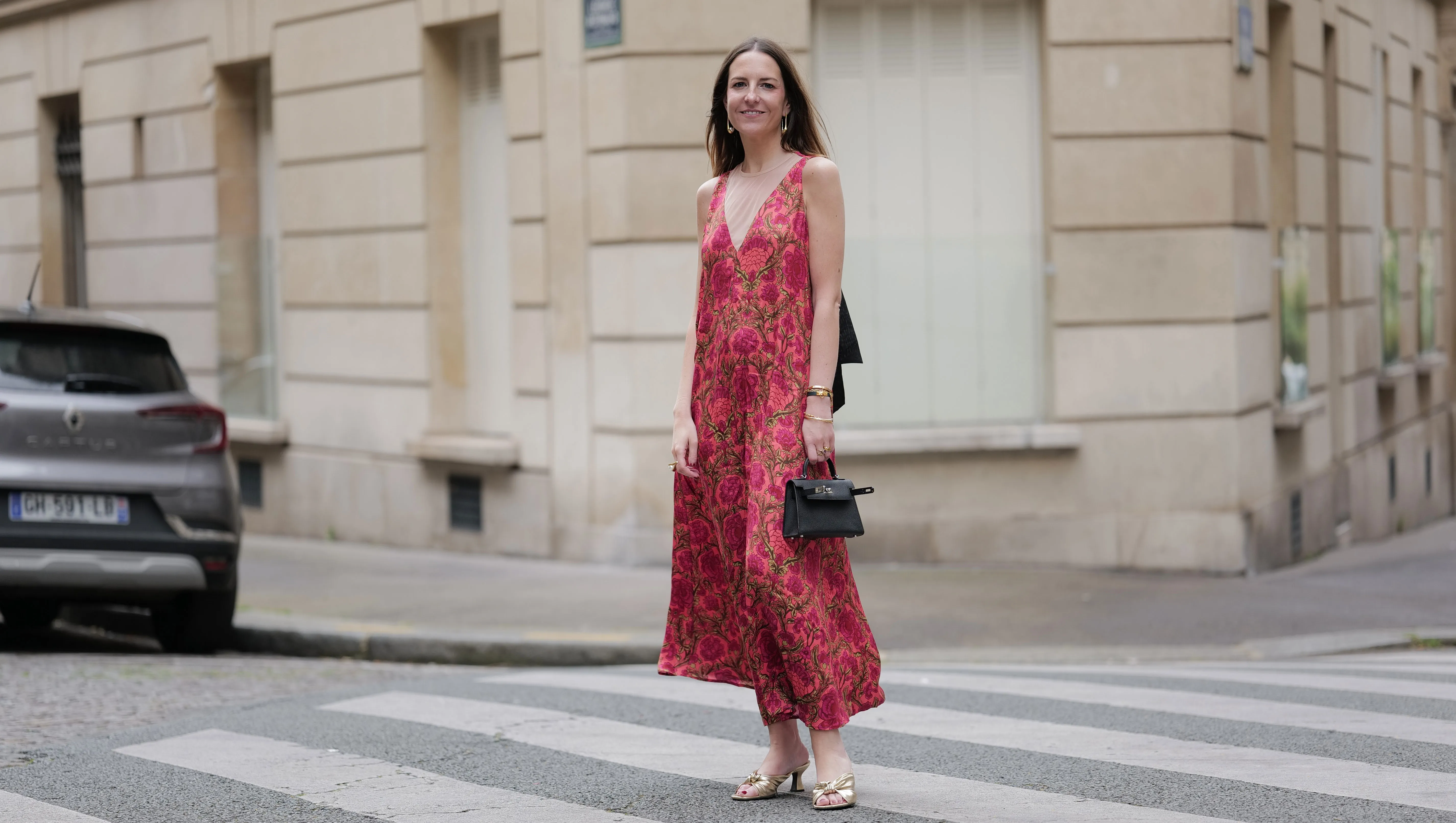 PARIS, FRANCE - JUNE 10: Alba Garavito Torre wears a red Flower print long dress with a tulle collar and black cotton tarsier bow on the neck from Frambua, gold kitten heel sandals, a black mini Kelly bag from Hermes, during a street style fashion photo session, on June 10, 2024 in Paris, France. (Photo by Edward Berthelot/Getty Images)