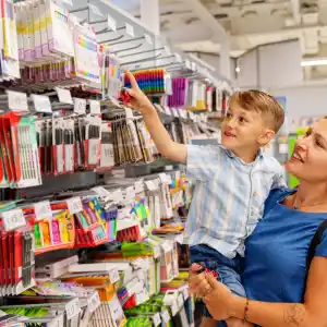 A child excitedly shopping for stationery on his mother's lap
