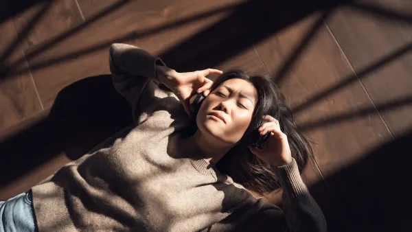 Woman in a brown sweater listening to music