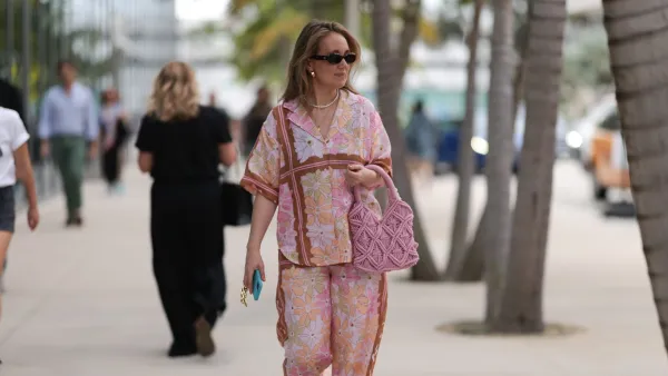 MIAMI, FLORIDA - DECEMBER 08: Anna Sophie seen wearing Le Specs brown oval sunglasses, gold earrings and necklace, pearl necklace, pink colorful floral print pattern shirt / blouse, matching pink colorful floral print pattern long pants, pink crochet handbag and black leather sandals, on December 08, 2023 in Miami, Florida. (Photo by Jeremy Moeller/Getty Images)