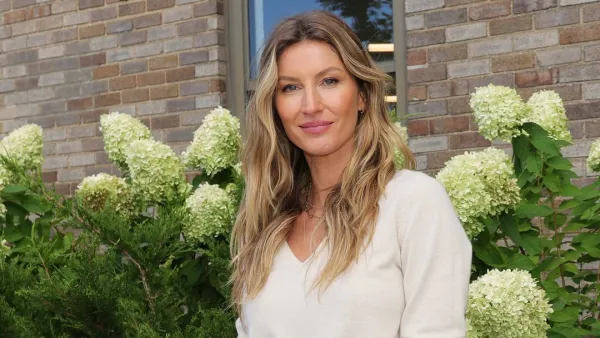 Gisele Bundchen standing in front of flowers