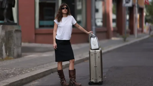 BERLIN, GERMANY - JULY 11: Lea Naumann is seen wearing black sunglasses from Prada, a white tee from Mother Denim, a black knee-length vintage skirt, brown leather boots with silver buckle closure from Miu Miu, a white leather Supernova bag from Prada and a silver suitcase from Rimowa on July 11, 2023 in Berlin, Germany. (Photo by Jeremy Moeller/Getty Images)