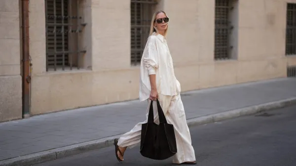 MUNICH, GERMANY - JUNE 18: Mirja Klein is seen wearing a matching set consisting of a white striped oversized dobby-weave shirt with collar and buttons down in the front from H&M and a white striped straight pull-on trousers with loose fit and straight legs from H&M; a black suede tote bag with slouchy design and open top from COS; black oversized aviator sunglasses from Tom Ford; a pair of khaki green suede flip flops from A.EMERY on June 18, 2025 in Munich, Germany. (Photo by Moritz Scholz/Getty Images)