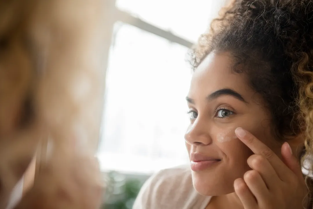 Woman applying lotion to her face