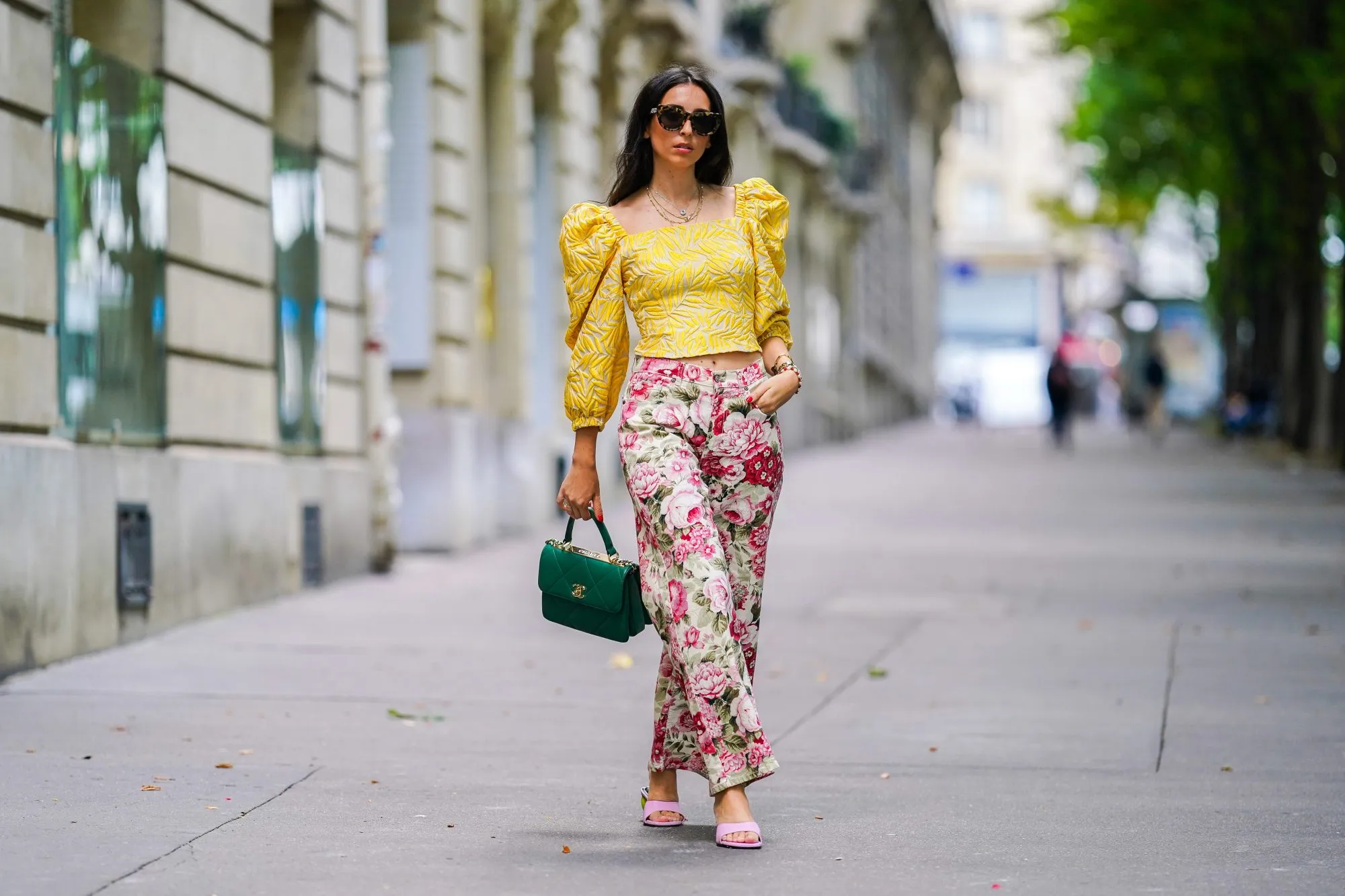 PARIS, FRANCE - JUNE 15: Street style photo session with Gabriella Berdugo wearing Kenzo sunglasses, a yellow ruffled top with puff sleeves and shoulder pads from Avavav, pink Yuulie shoes, a green quilted Chanel bag, pink floral print flared pants from Parosh, a necklace, a watch, on June 15, 2020 in Paris, France. (Photo by Edward Berthelot/Getty Images)