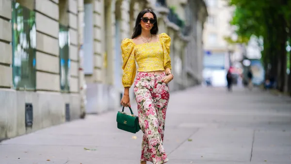 PARIS, FRANCE - JUNE 15: Street style photo session with Gabriella Berdugo wearing Kenzo sunglasses, a yellow ruffled top with puff sleeves and shoulder pads from Avavav, pink Yuulie shoes, a green quilted Chanel bag, pink floral print flared pants from Parosh, a necklace, a watch, on June 15, 2020 in Paris, France. (Photo by Edward Berthelot/Getty Images)