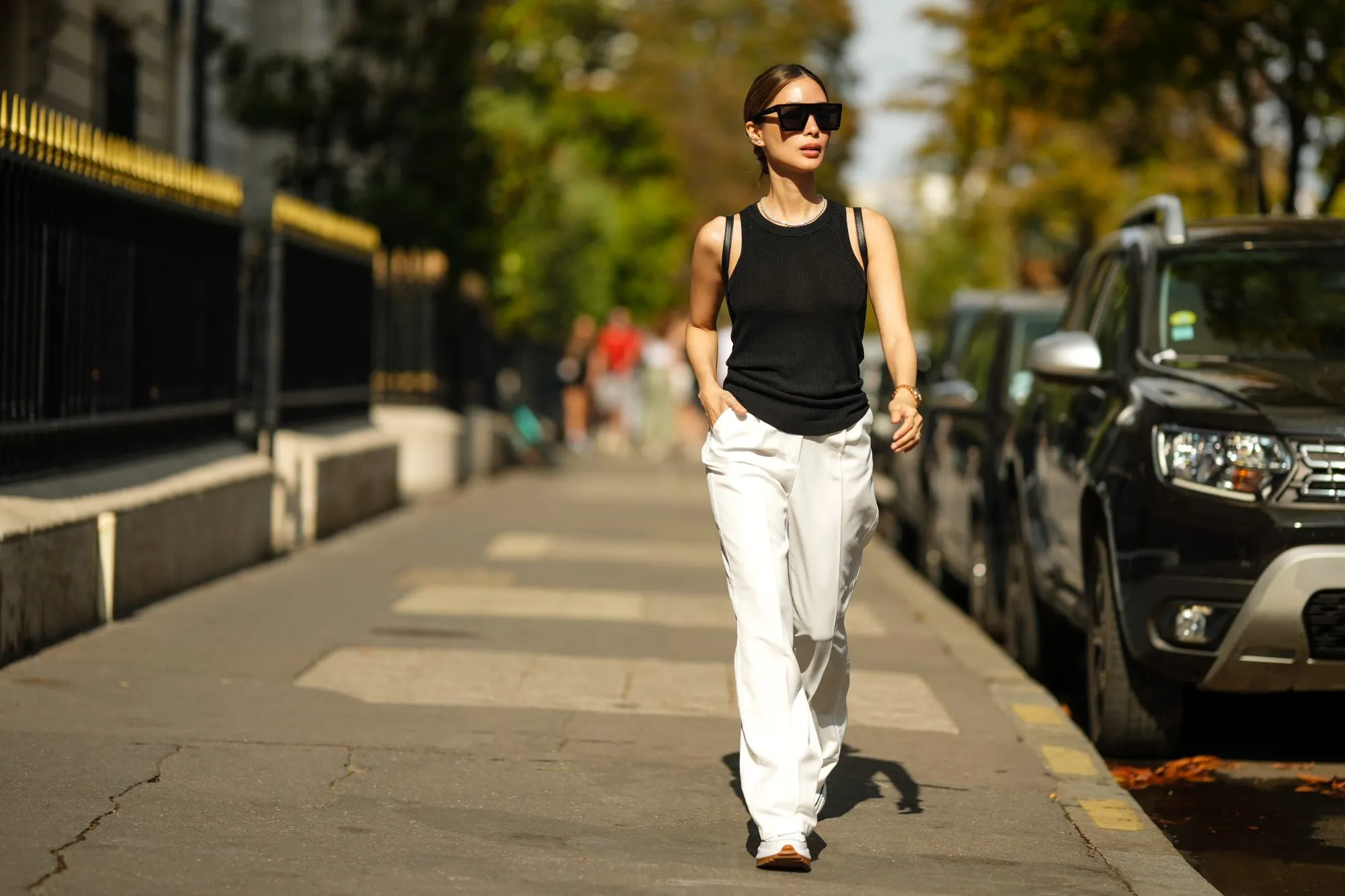 PARIS, FRANCE - AUGUST 30: Heart Evangelista wears sunglasses, a black tank top, white flare wide-leg jeans, Converse sneakers / shoes, during a street style fashion photo session, on August 30, 2022 in Paris, France. (Photo by Edward Berthelot/Getty Images)