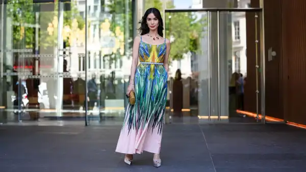 PARIS, FRANCE - JULY 09: Heart Evangelista wears a sleeveless maxi dress featuring a vibrant, multicolored abstract pattern with shades of blue, green, yellow, and pink. The dress has thin straps and a fitted bodice, transitioning into a flowing skirt. A thin belt in a neutral tone cinches the waist. Accessories include a gold-toned clutch with a textured surface and a statement necklace with red accents. Footwear consists of light-colored platform heels. Hair is styled in loose waves, and makeup is subtle with a focus on natural tones, outside Elie Saab, during Paris Fashion Week - Haute Couture Fall/Winter 2025/2026, on July 09, 2025 in Paris, France (Photo by Edward Berthelot/Getty Images)