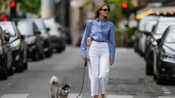 PARIS, FRANCE - MAY 20: Segolene Hyppolite wears sunglasses, a blue and white oversized shirt from Tommy Hilfiger, a raffia beige bag from Vanessa Bruno, high waist white denim pants from Vanessa Bruno, Chanel slingback shoes in blue denim with black tips, walks with her husky dog /pet which she holds with a striped leash, during a street style fashion photo session, on May 20, 2024 in Paris, France. (Photo by Edward Berthelot/Getty Images)