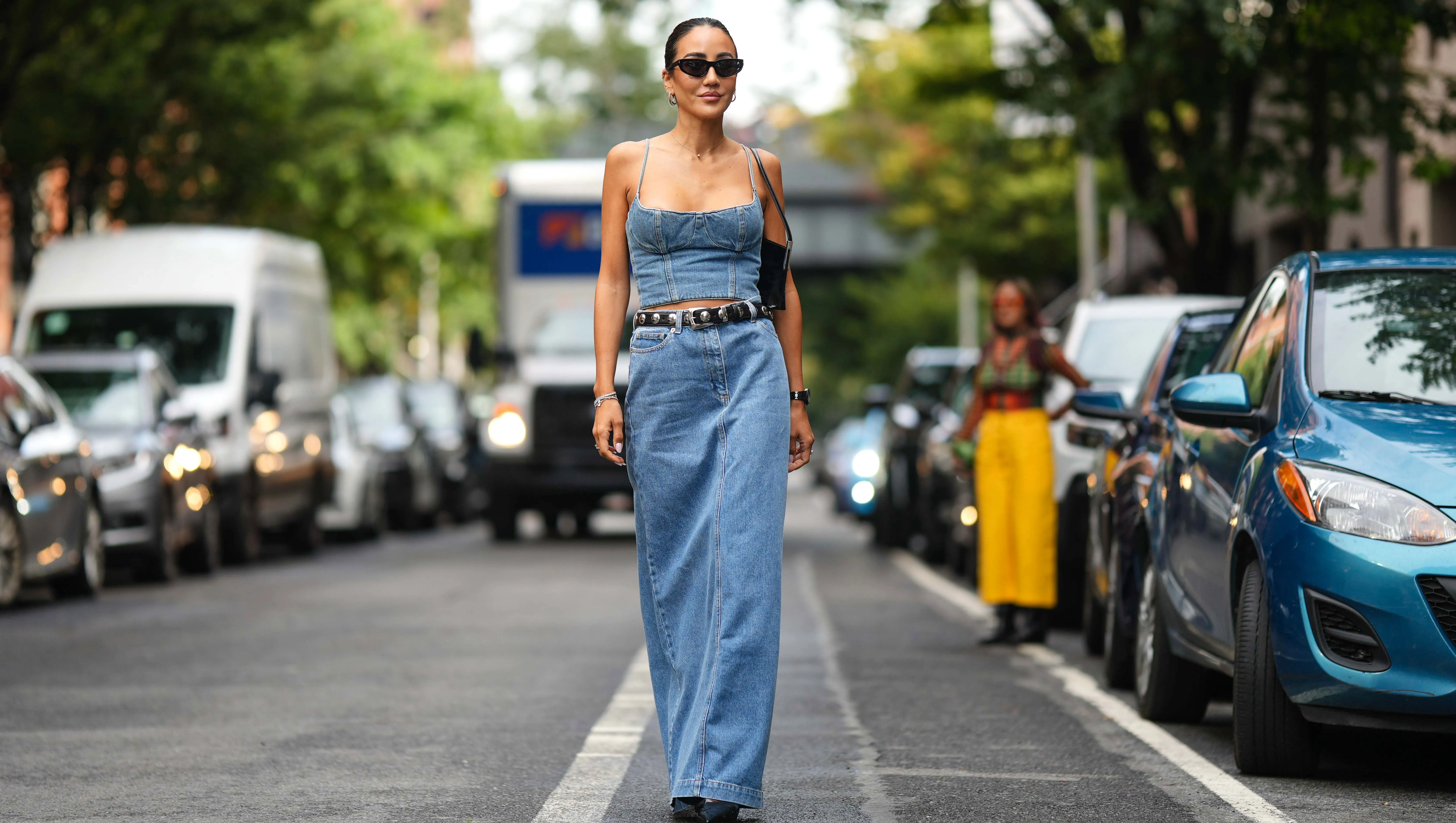 NEW YORK, NEW YORK - SEPTEMBER 10: Tamara Kalinic wears sunglasses, a blue denim off-shoulder low neck cropped top, a black leather studded belt, a blue denim maxi skirt, a black leather bag, outside Adeam, during New York Fashion Week, on September 10, 2023 in New York City. (Photo by Edward Berthelot/Getty Images)