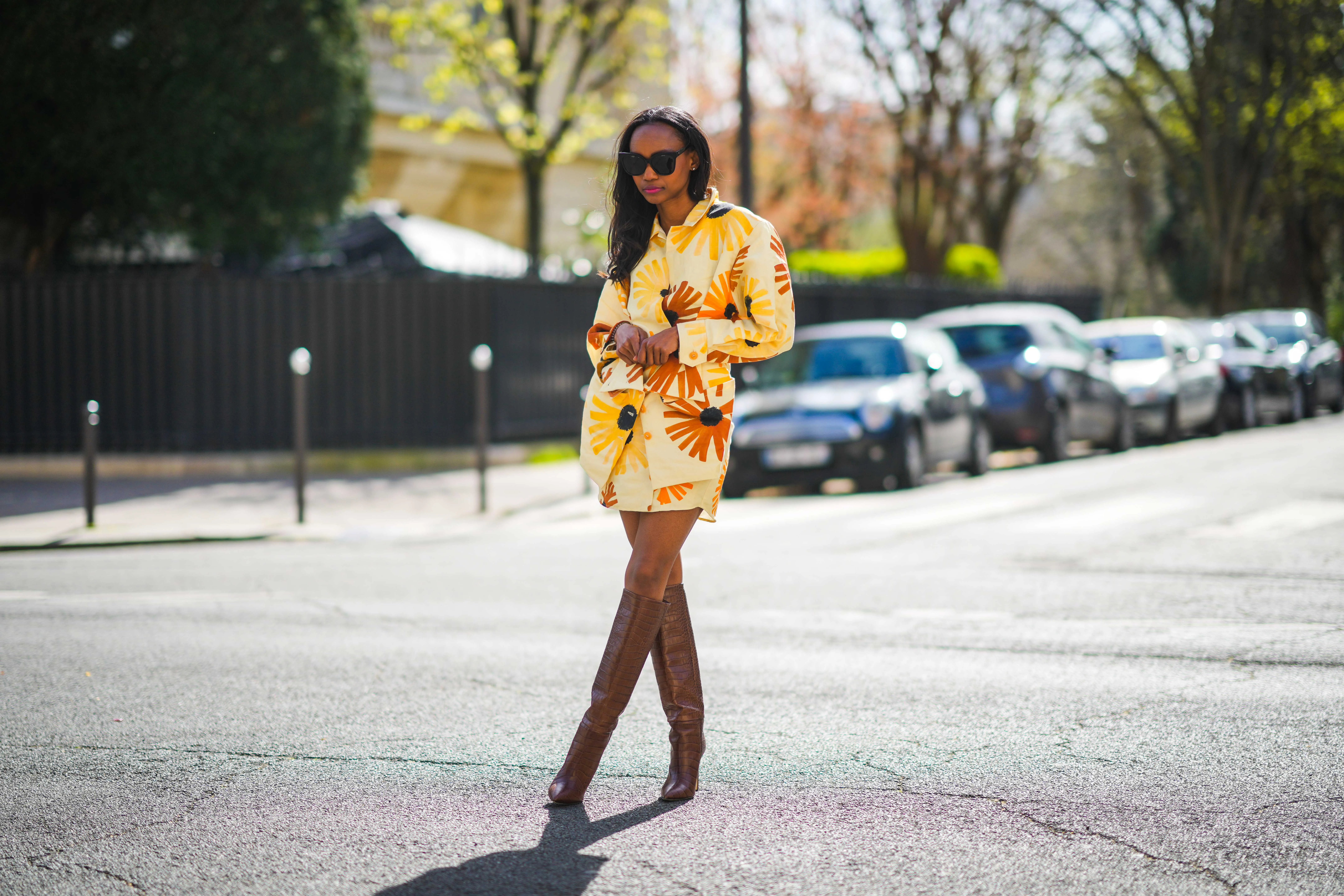 Emilie Joseph @in_fashionwetrust wears a yellow and orange floral print Jacquemus Murano dress with flap pockets and buttoned waist, Boots with Croc-effect leather knee-high boots from Paris Texas, on March 28, 2021 in Paris, France.