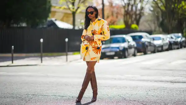 Emilie Joseph @in_fashionwetrust wears a yellow and orange floral print Jacquemus Murano dress with flap pockets and buttoned waist, Boots with Croc-effect leather knee-high boots from Paris Texas, on March 28, 2021 in Paris, France.
