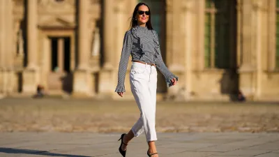 Alba Garavito Torre wears a gingham checkered black and white shirt with Long Sleeve Ruffles from Serendipia, Mom jeans in white from Maison 123 Paris, a brown leather thin belt, Black Mary Jane high heels shoes from Gucci, on October 10, 2021 in Paris, France.