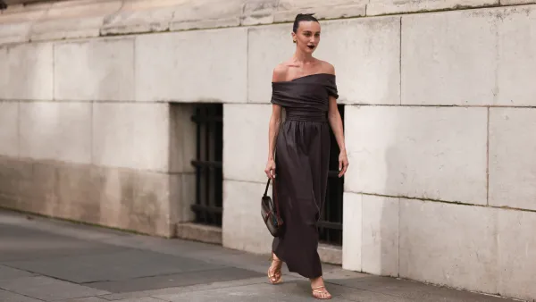 Mary Leest is seen outside Altuzarra show wearing golden earrings, brown leather wrapped around long dress, a brown handbag and golden lace up heels on September 11, 2023 in New York City.