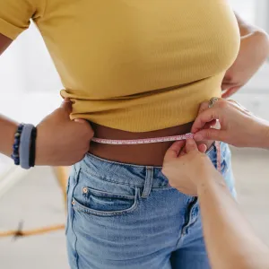 Diabetologist doctor measuring patient’s waist, examine abdominal obesity in diabetes clinic. Patient diagnosed with diabetes.