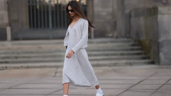 Jill Asemota seen wearing black vintage sunglasses, Dorothee Schumacher grey wool knit long dress, matching Dorothee Schumacher grey wool knit cardigan jacket, white cotton socks, Adidas white leather Samba sneakers, on November 04, 2023 in Berlin, Germany.