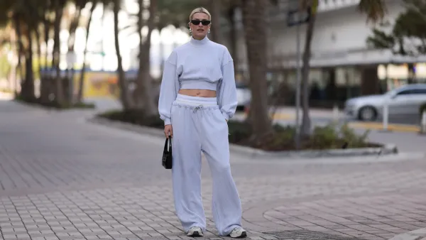 MIAMI, FLORIDA - DECEMBER 08: Lena Gercke seen wearing Saint Laurent black sunglasses, silver statement necklace, Alexander Wang light grey high neck cotton cropped jumper / sweater, Alexander Wang light grey cotton wide leg jogger pants with underwear detail, Saint Laurent black varnishes leather mini bag and Axel Arigato white leather sneakers, on December 08, 2023 in Miami, Florida. (Photo by Jeremy Moeller/Getty Images)2